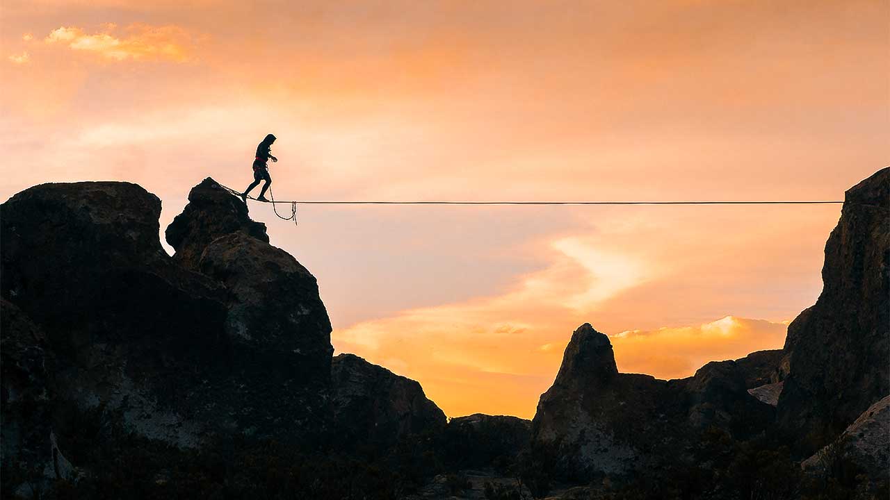 Mann balanciert auf einem Seil über Felsen