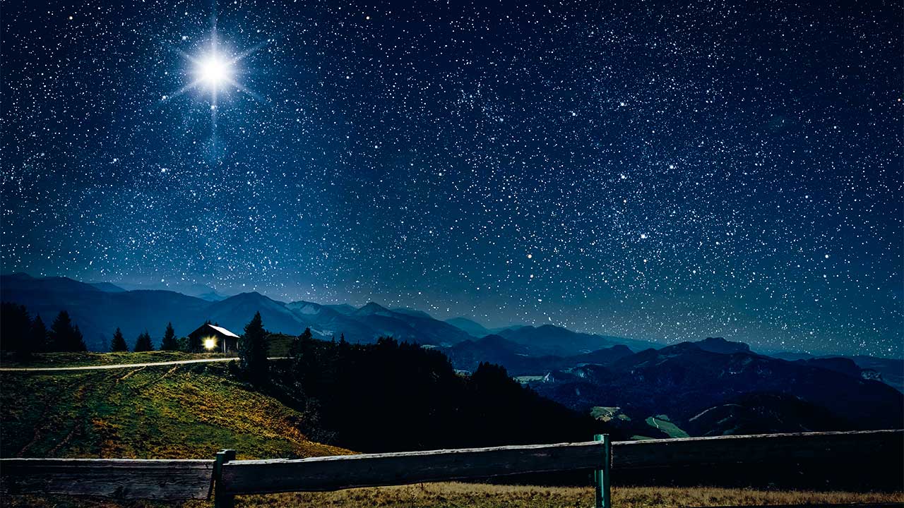 Sternenhimmel mit hellem Stern, unten eine erleuchtete Hütte