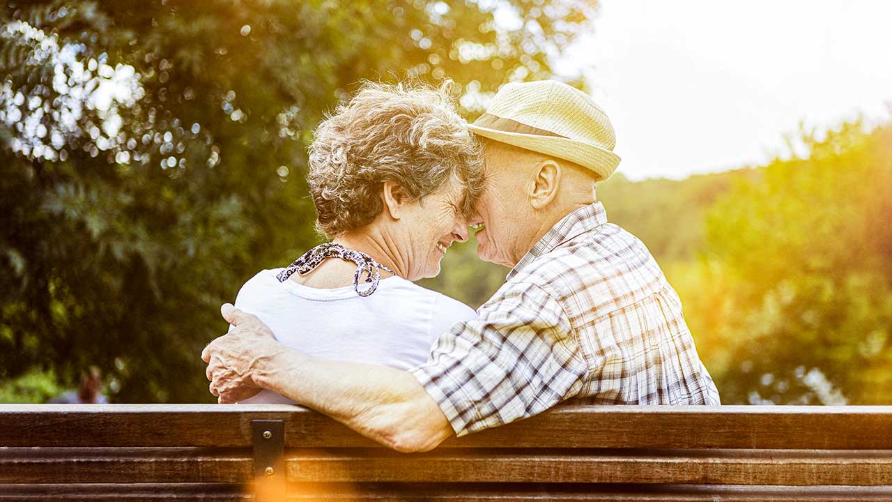 Seniorenpaar sitzt auf einer Bank und ist voller Zuneigung