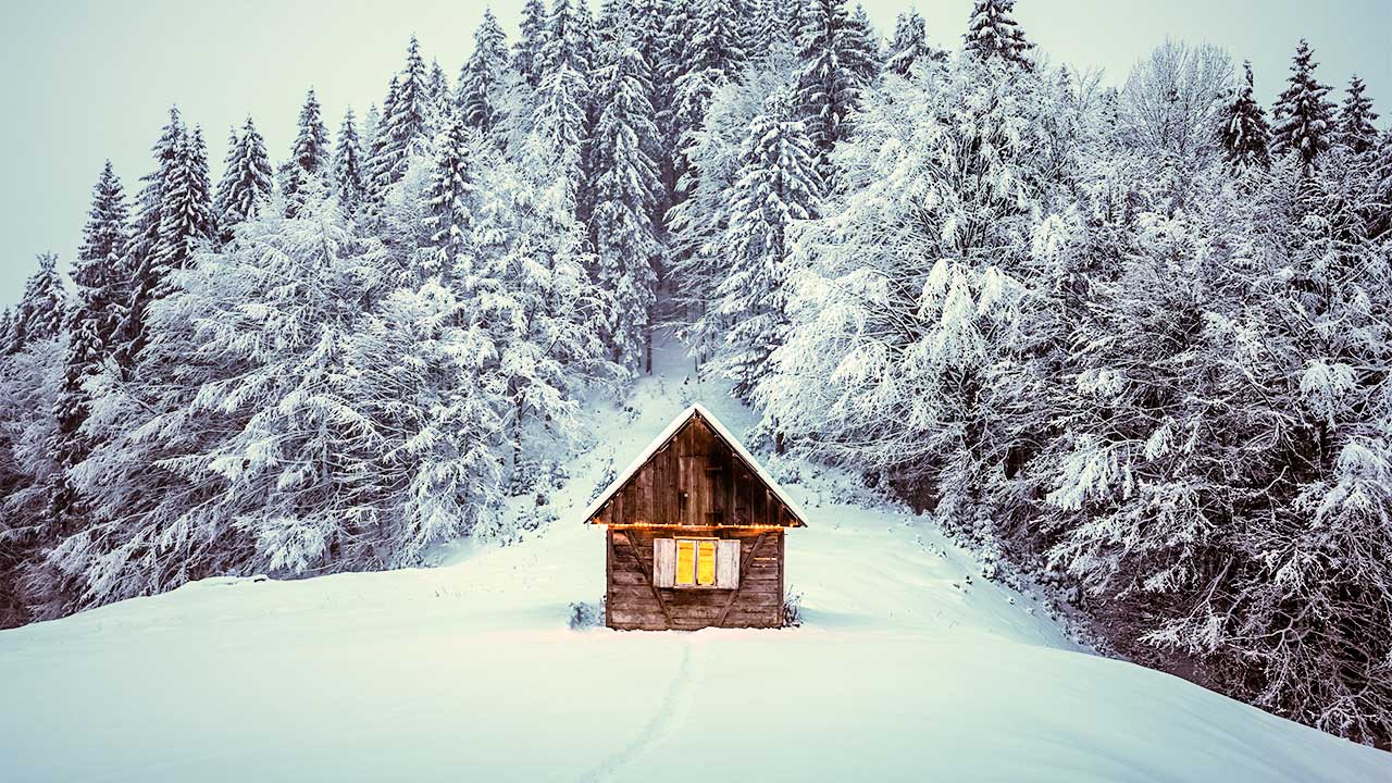 Beleuchtete Hütte in einer schneebedeckten Winterlandschaft