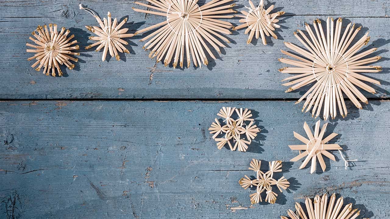 gelbliche gebastelte Weihnachtssterne auf blauem Holzhintergrund