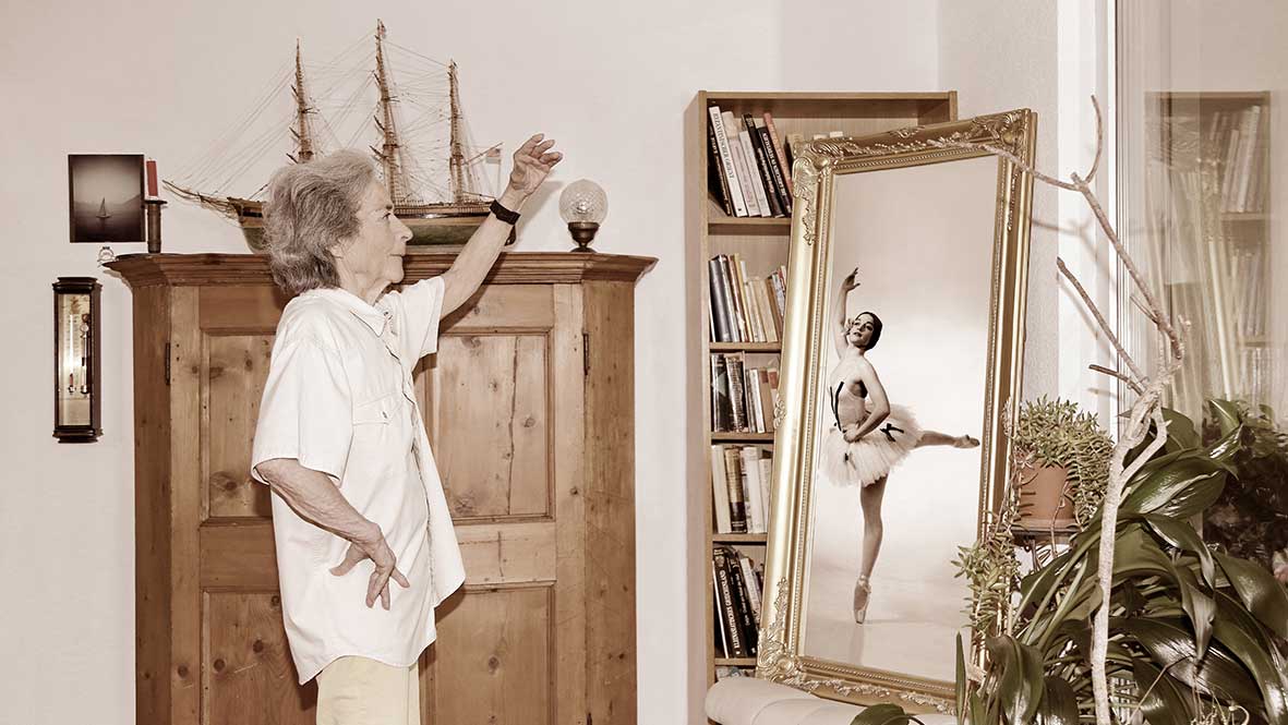 Seniorin mit ihrem jüngeren Spiegelbild im Rahmen der Ausstellung «WÄRTvou im Alter»