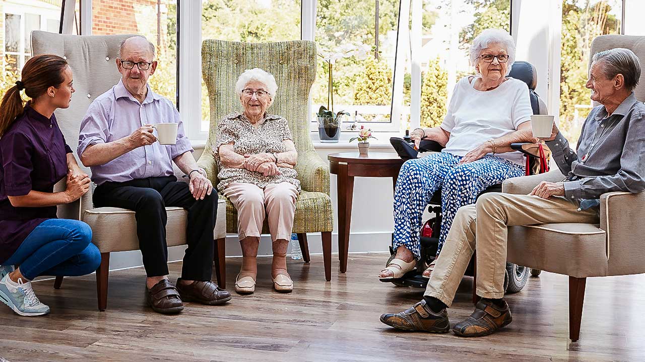 vier Senioren in einem Altersheim mit einer Pflegerin