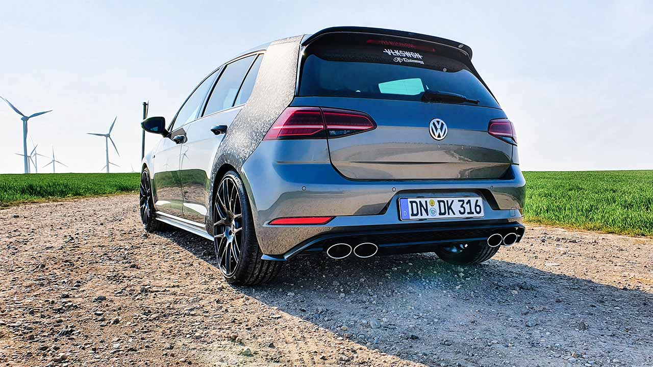 Auto der Marke Volkswagen steht auf einer Feldstrasse, im Hintergrund Windkrafträder