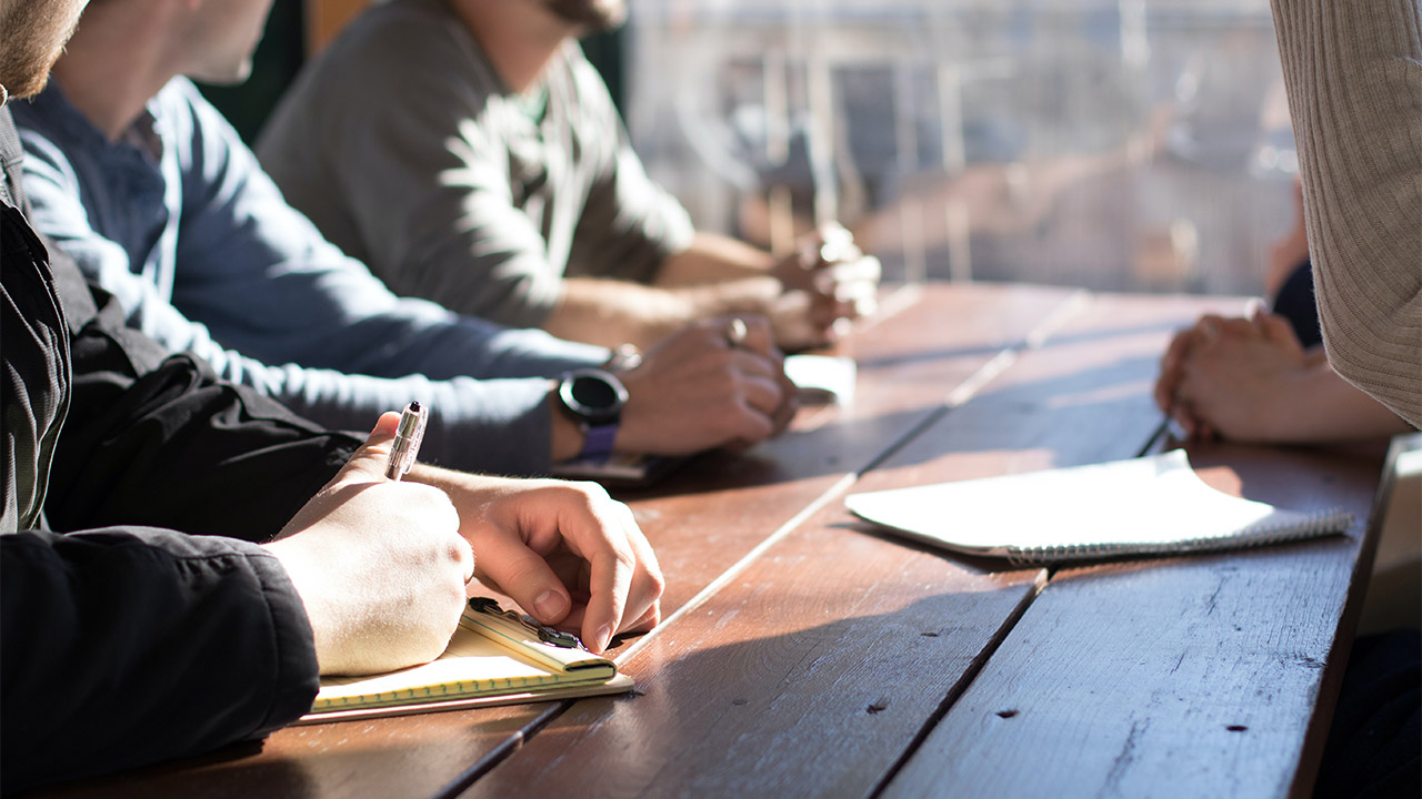 Leute sitzen zusammen an einem Tisch | (c) unsplash