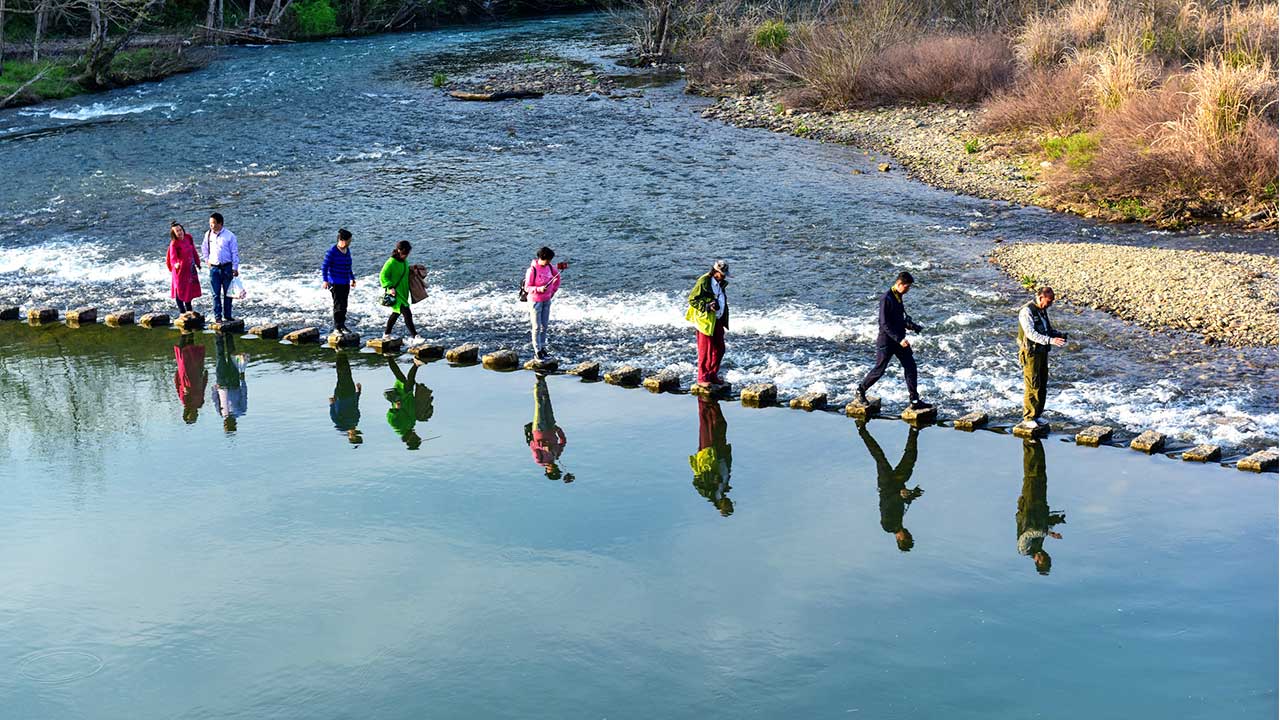 Von Stein zu Stein: Menschen laufen auf der Regenbogen-Brücke in Jianxi, China