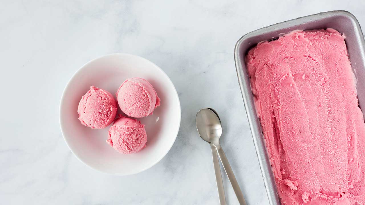 Rhabarber-Glace in Behälter und in einer Schüssel, dazwischen zwei Löffel