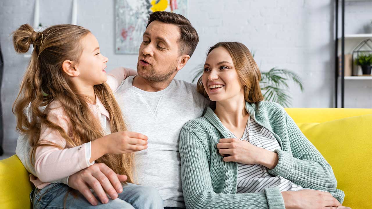 Eltern mit ihrer Tochter haben eine harmonische Zeit auf dem Sofa