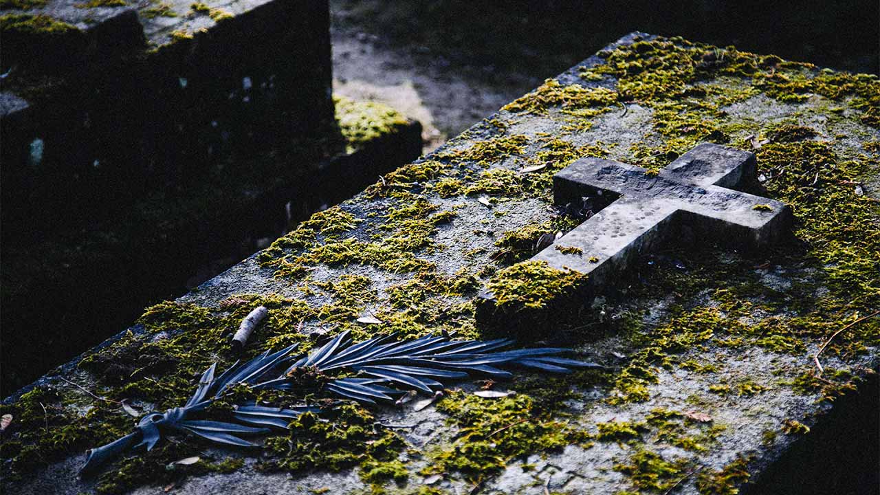 Blick auf einen steinernen Sarg, auf dem ein steinernes Kreuz liegt