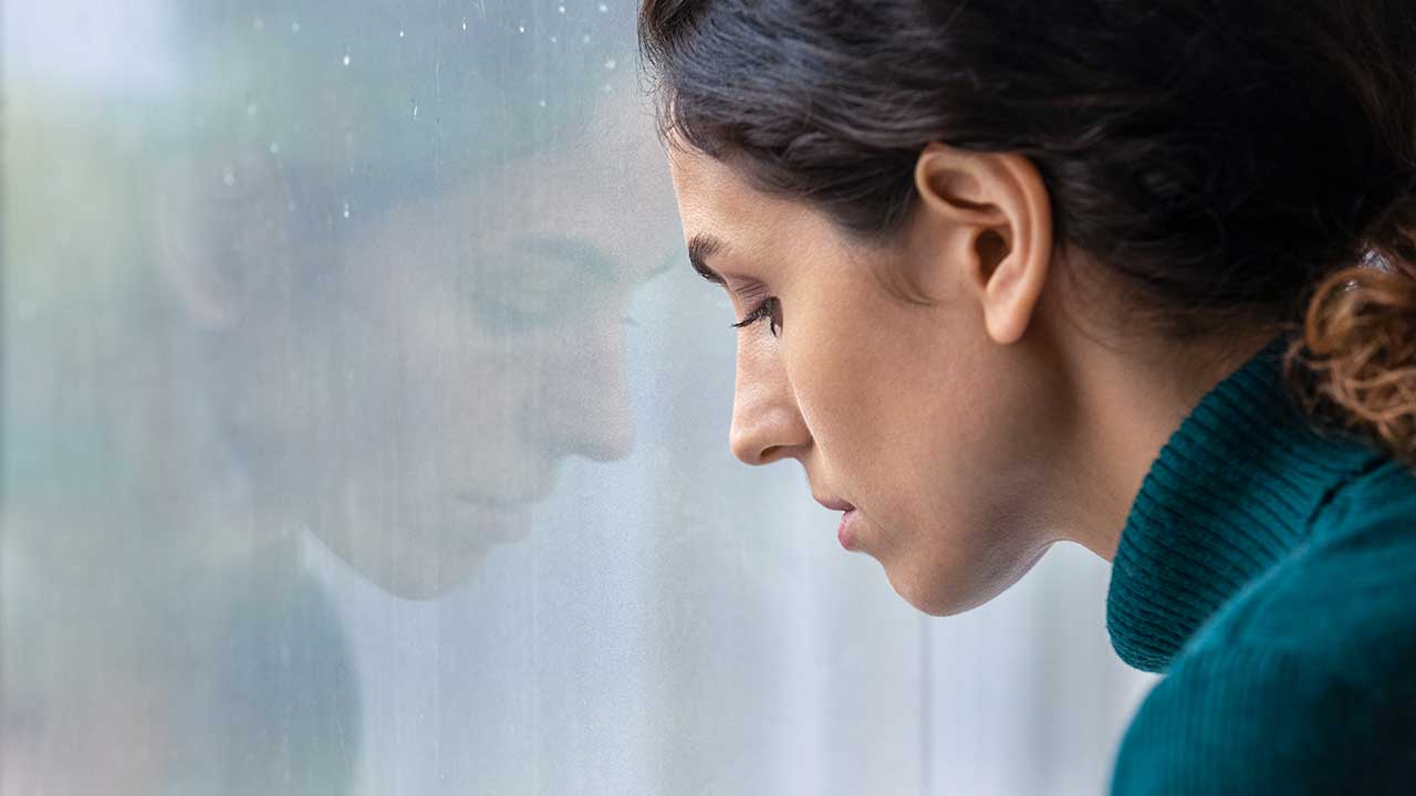 niedergeschlagene Frau an einem Fenster