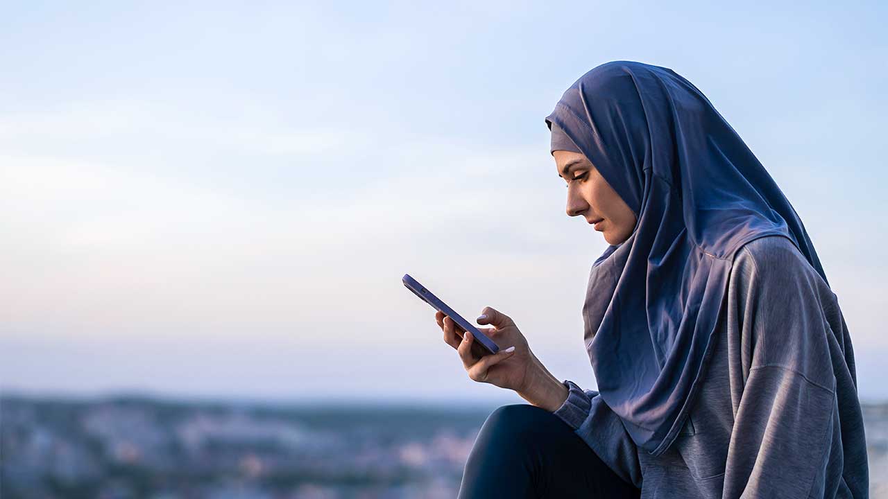 junge muslimische Frau im Hijab hält ein Smartphone in der Hand