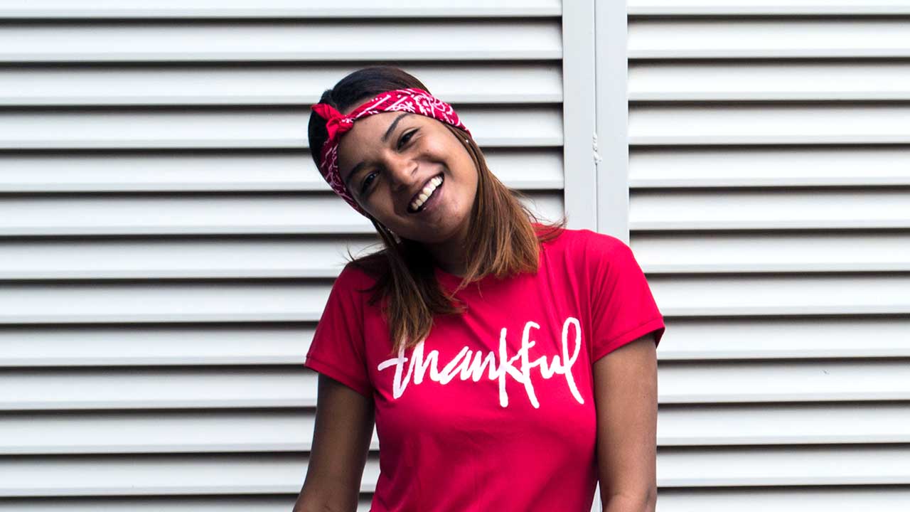 Fröhlich Frau trägt rotes T-Shirt mit der Aufschrift «thankful»