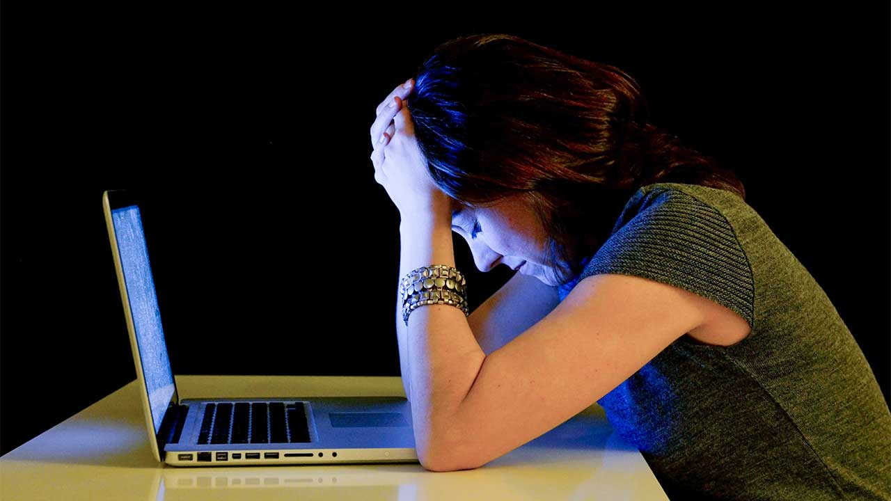 jüngere Frau sitzt trauernd vor einem Laptop