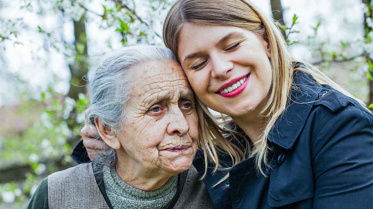 jüngere Frau zeigt Seniorin ihre Zuneigung