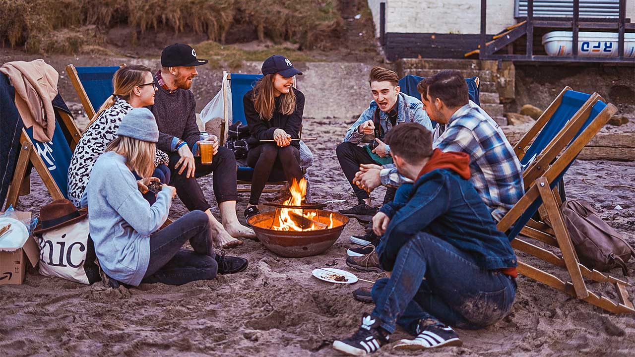 junge Menschen sitzen um ein Feuer herum und haben Gemeinschaft