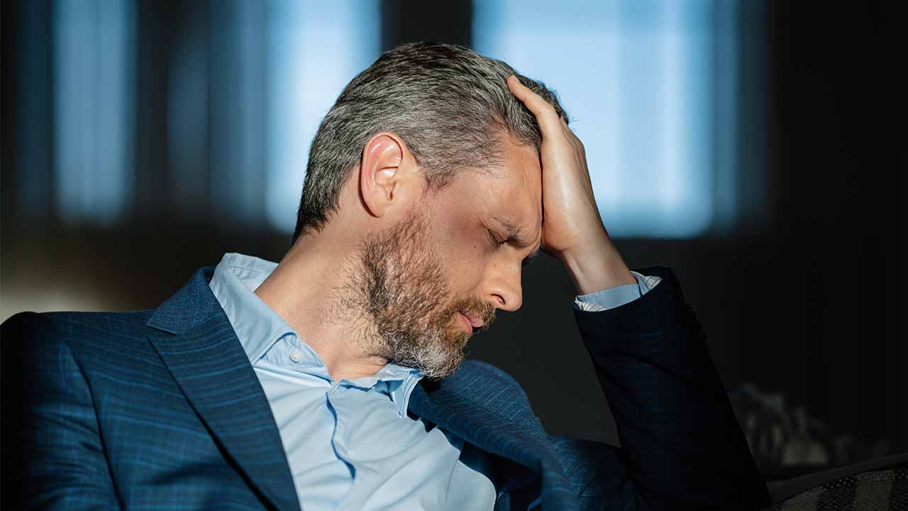 müder und erschöpfter Geschäftsmann hält seinen Kopf in eine Hand