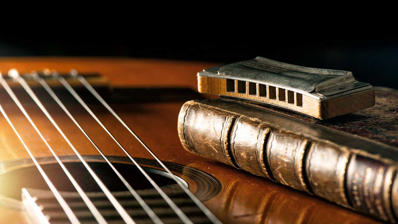 akustische Gitarre mit Mundharmonika und altem Buch