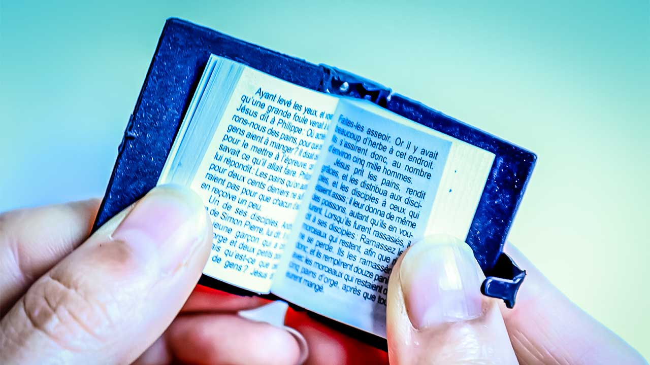 Hände halten Mini-Bibel in Französisch