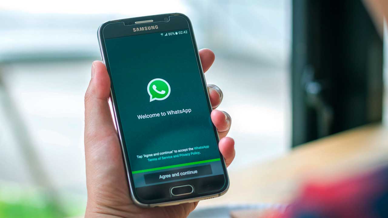 Hand hält Smartphone mit WhatsApp-Startbildschirm