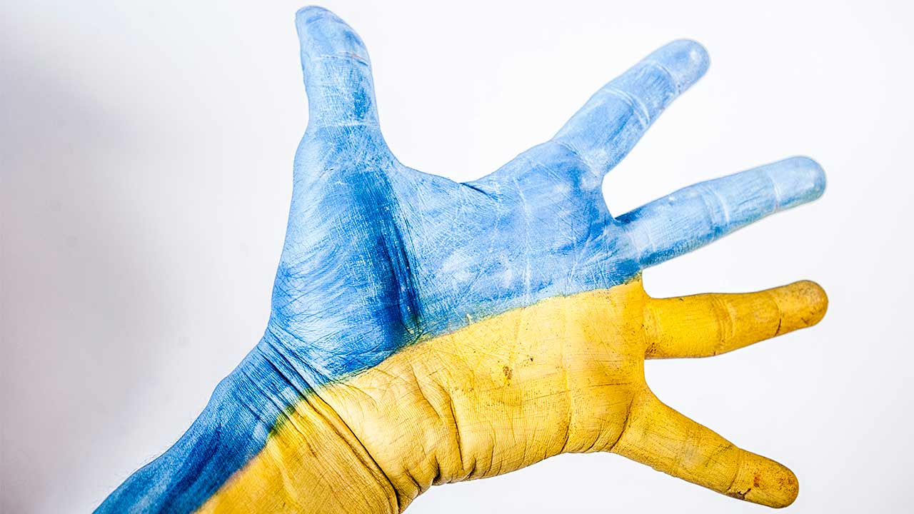 Ausgestreckte Hand in blau und gelb, den Farben der Ukraine