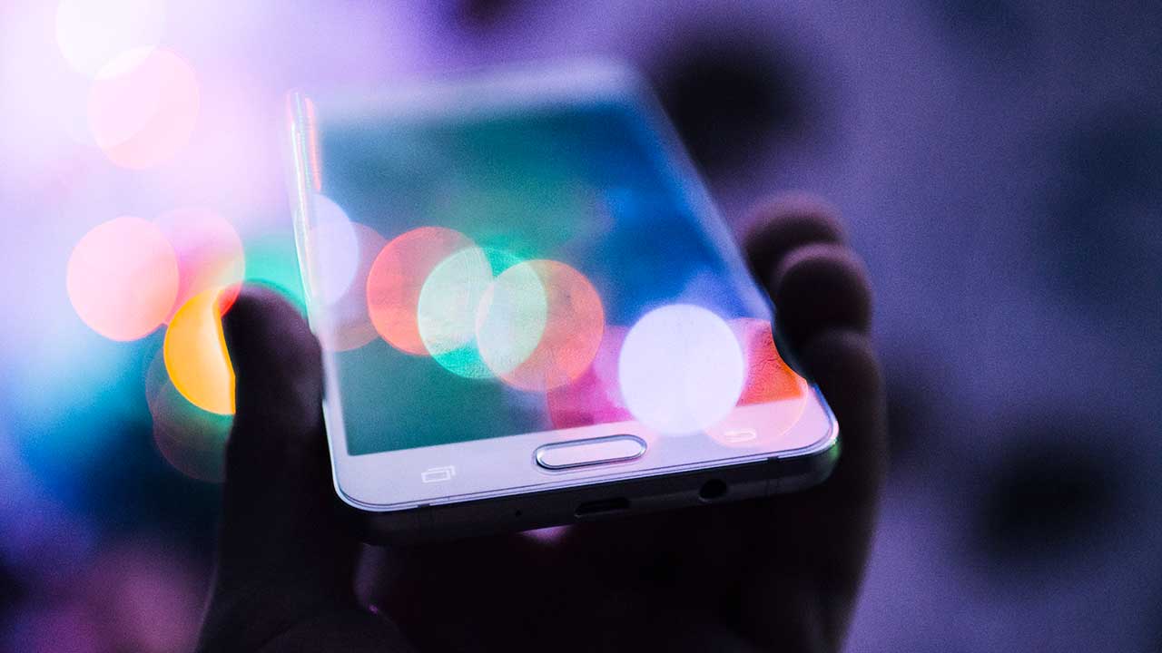 Hand in dämmrigem Licht hält Smartphone