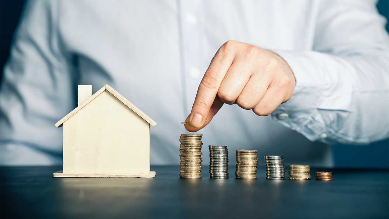 Holzhaus und Münzen als Symbolik für Sparen auf den Hauskauf