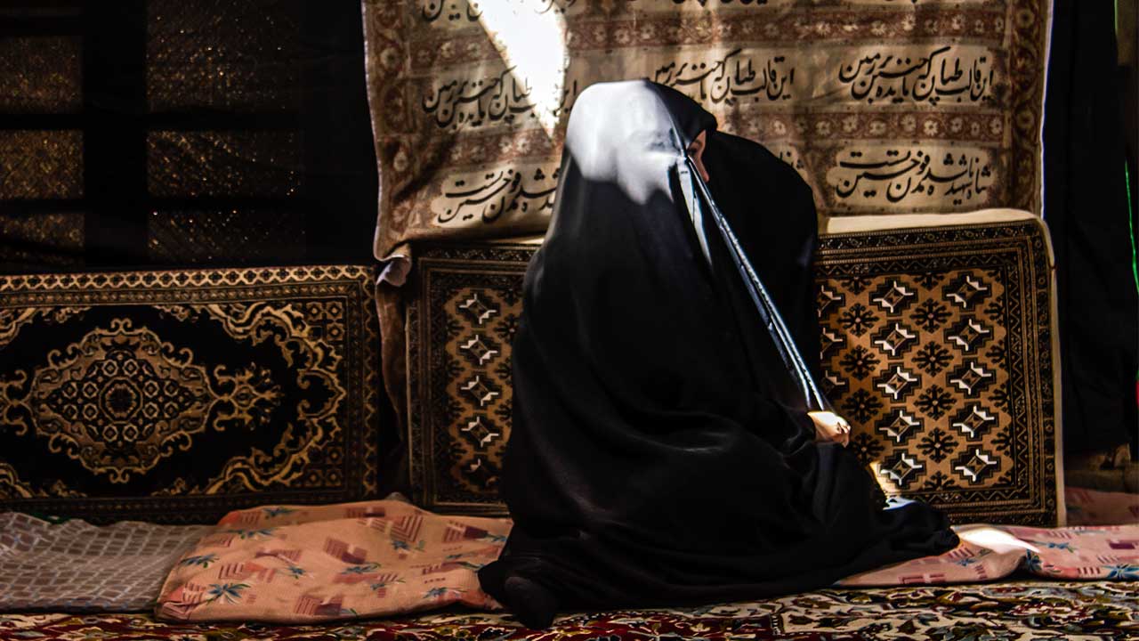 verschleierte iranische Frau wird von oben von einem Lichtstrahl beleuchtet
