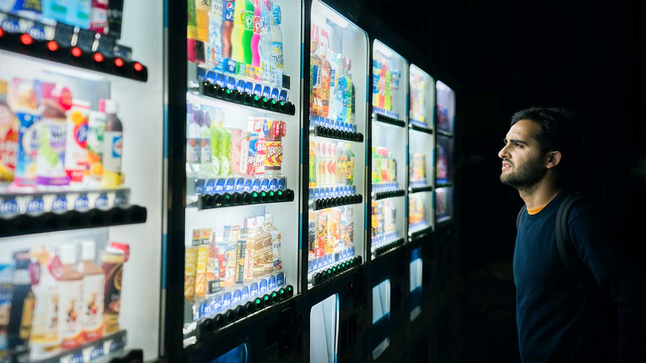 Nicht-Japaner blickt in Tokio an Automaten mit Getränkeflaschen