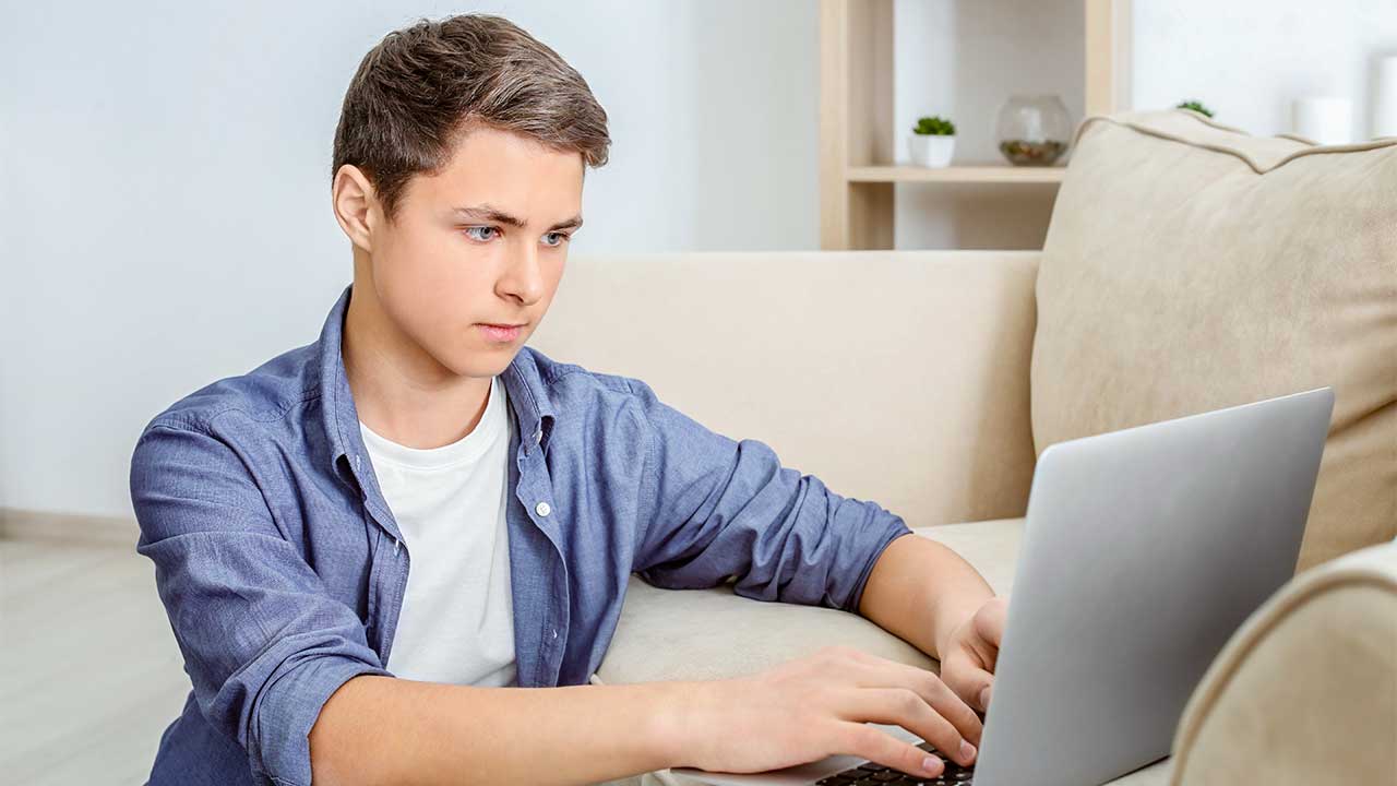 Jugendlicher arbeitet konzentriert mit einem Laptop
