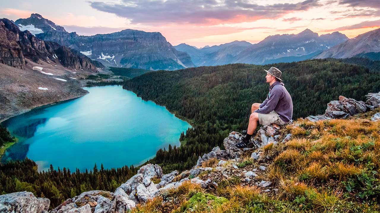 Mann sitzt oberhalb von einem Bergsee in Kanada