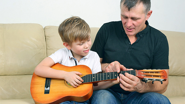 Vater zeigt gegenüber seinem Sohn Lernen des Gitarrenspiels Geduld