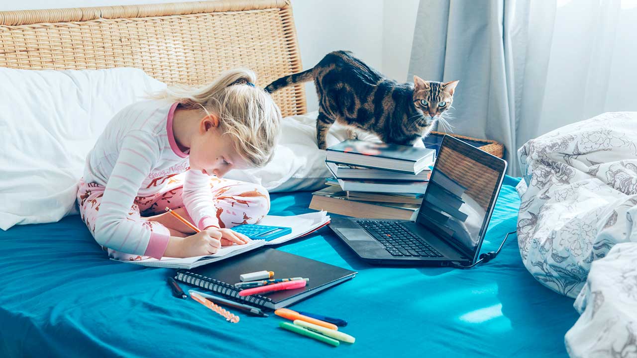 Mädchen lernt auf ihrem Bett, mit Büchern und Laptop
