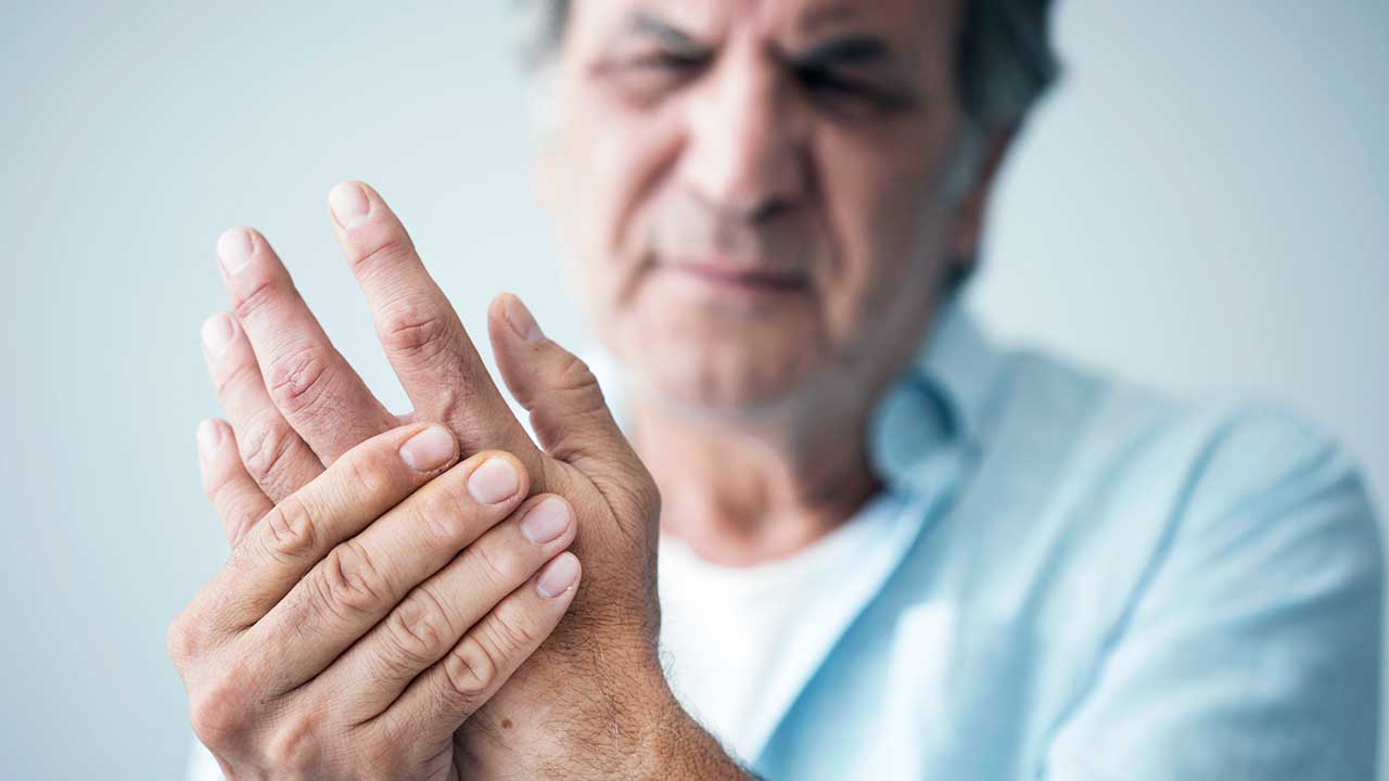 Mann hält Hände, weil seine Finger schmerzen