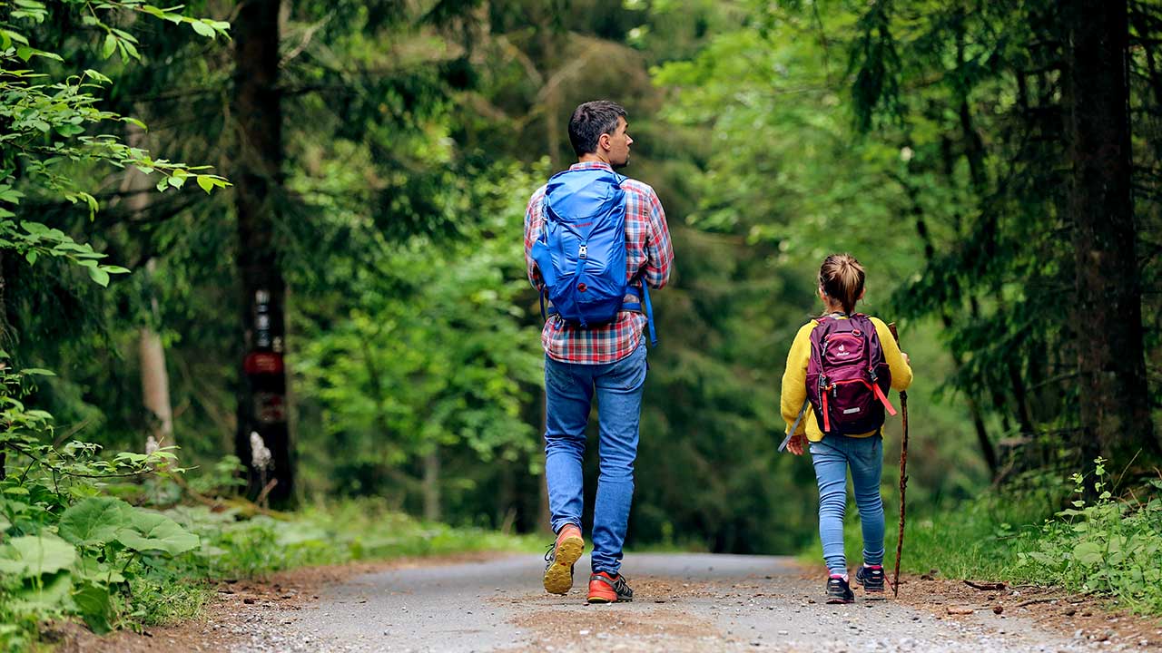 Vater und Tochter wandern zusammen auf einem Waldweg