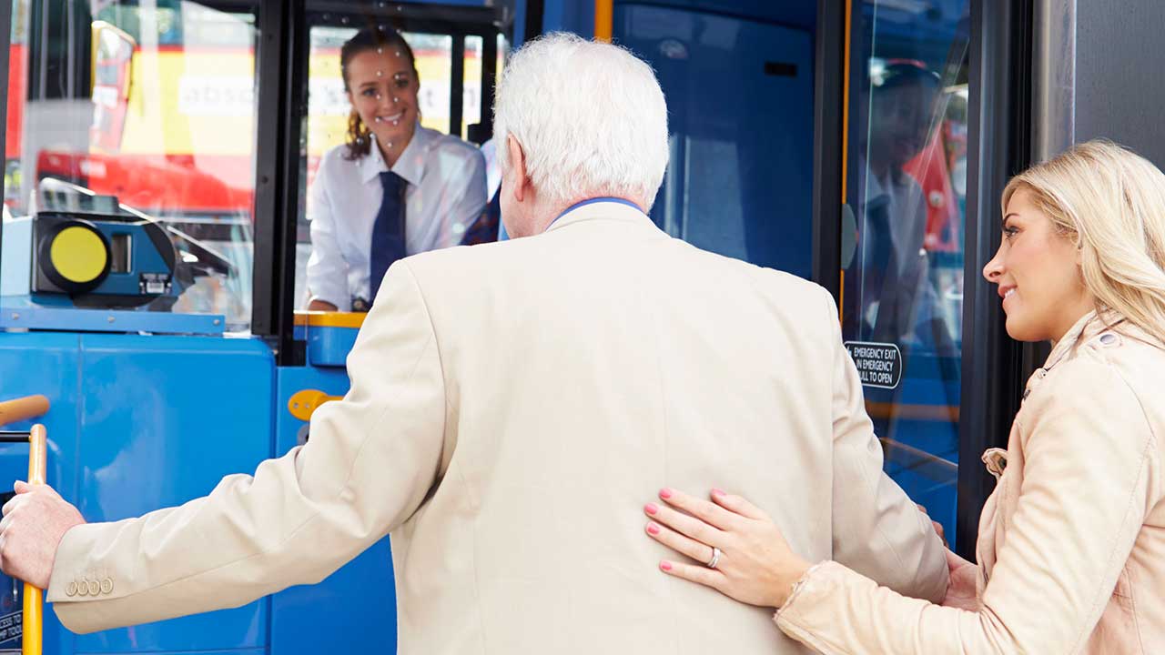 Frau hilft einem älteren Mann in den Bus