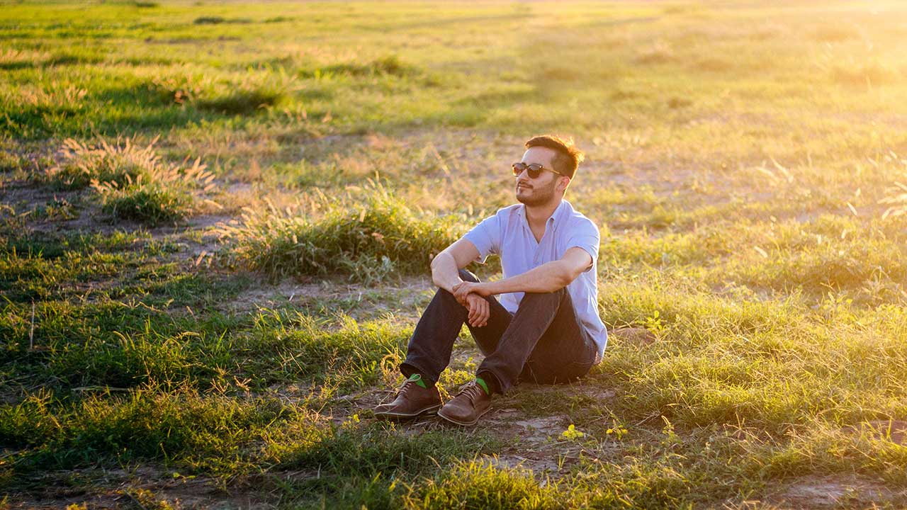 Mann sitzt im Sommer auf Gras und ruht sich aus