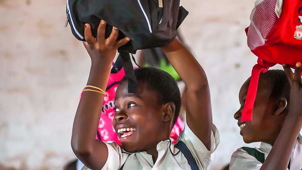 Afrikanische Kinder freuen sich an Rucksäcken aus der Schweiz