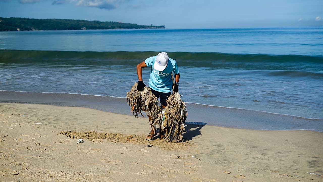 Freiwilliger sammelt an einem Strand ein grosses Stück Abfall ein