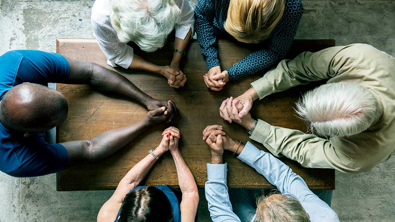 Menschen beten zusammen an einem Tisch