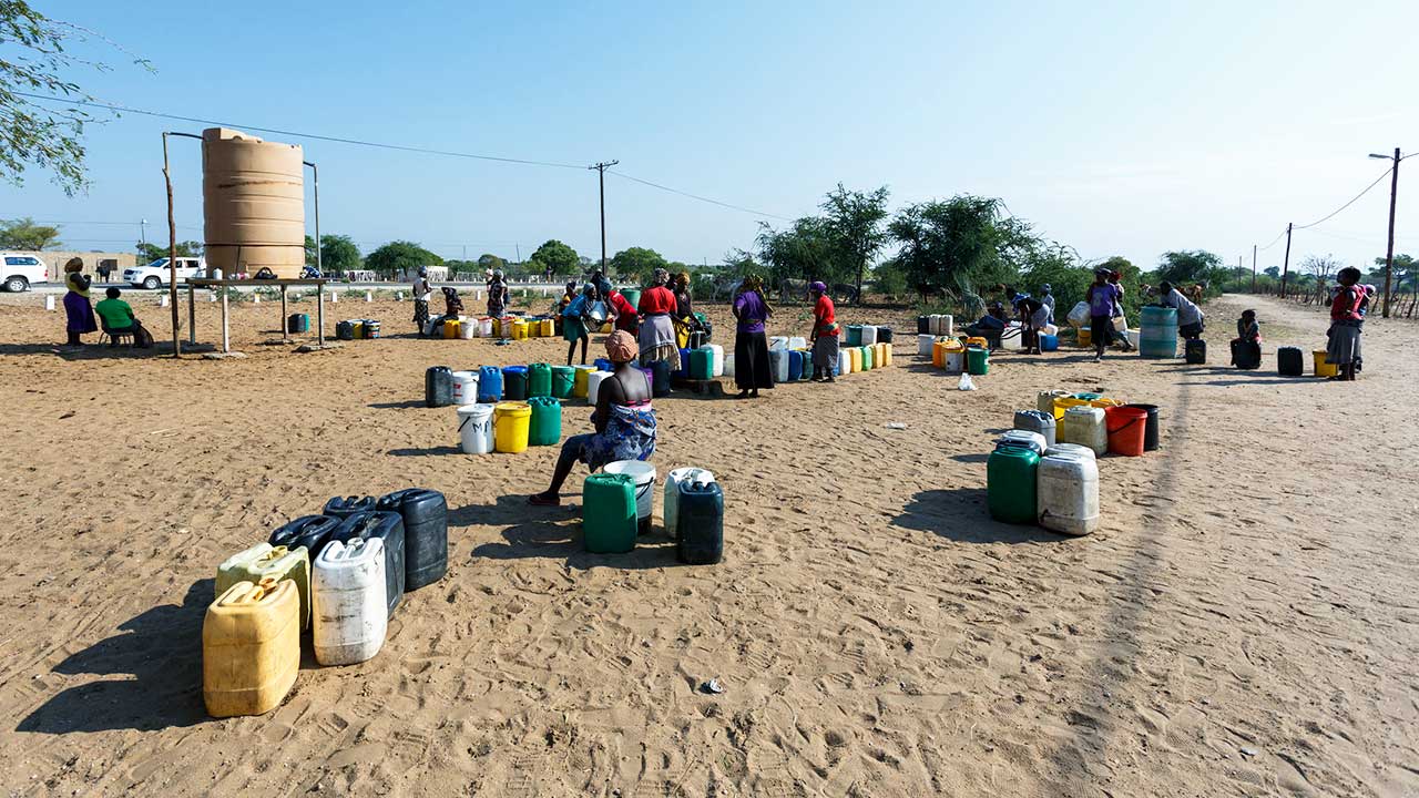 Menschen mit Behältern vor einem Wassertank in Namibia