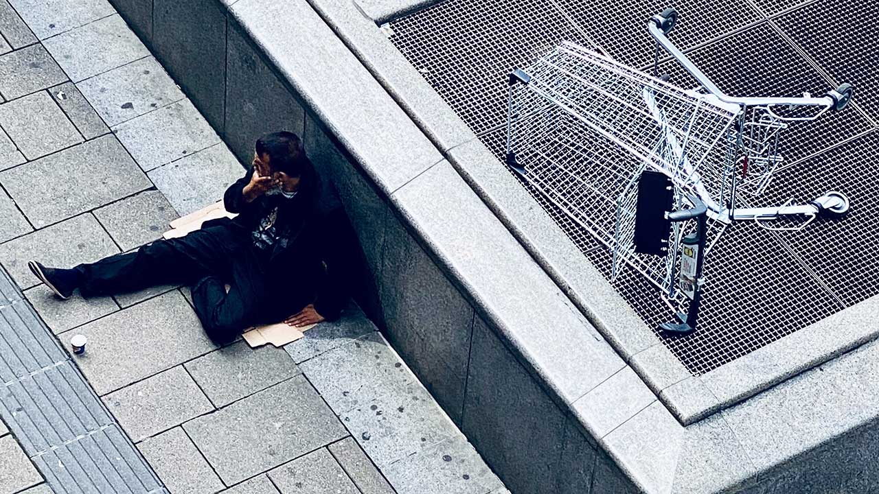 Bettelnder Mann in Wien sitzt vor Rolltreppe