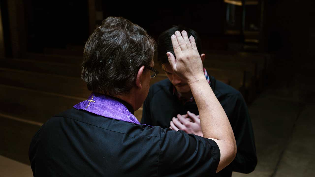 Priester segnet einen Mann, indem er eine Hand über den Kopf des anderen hält
