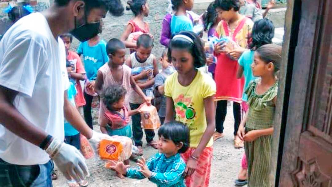 Ein Mitarbeiter von SAM global verteilt Nahrungsmittel an Kinder