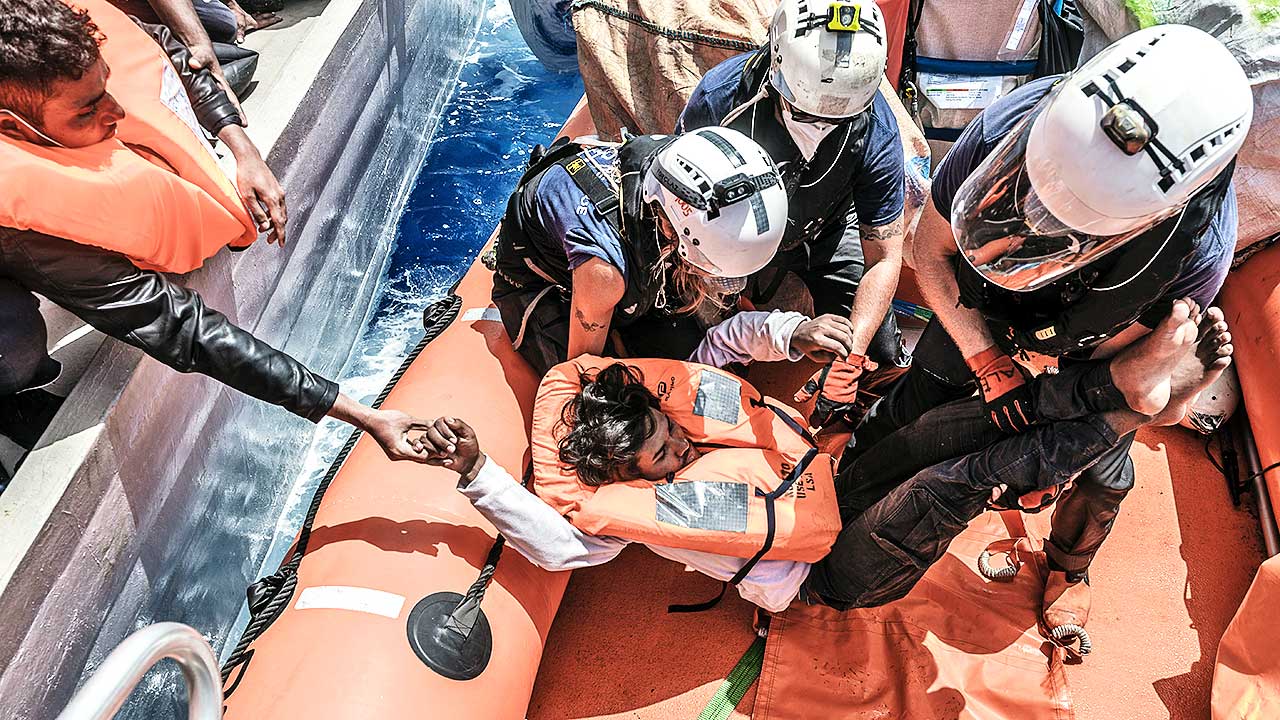 Besatzungsmitglieder der SOS Mediterranee retten einen Flüchtling