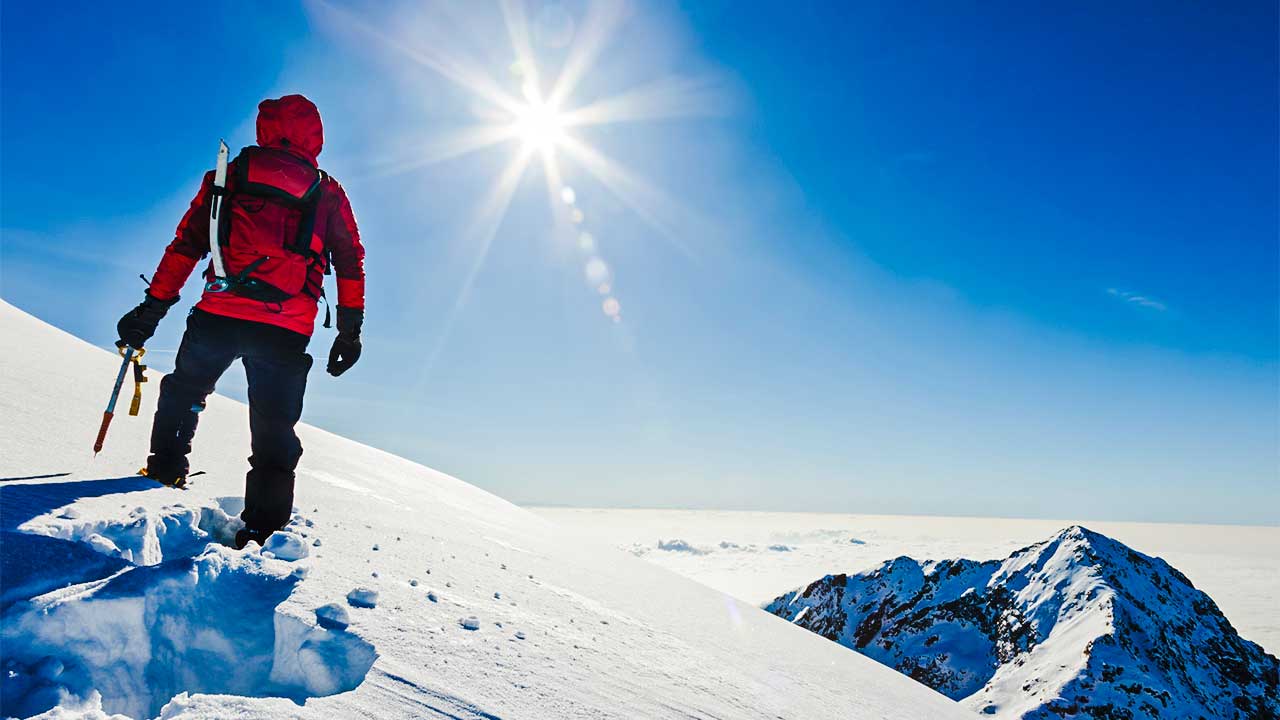 Bergsteiger im Schnee blickt Richtung Sonne