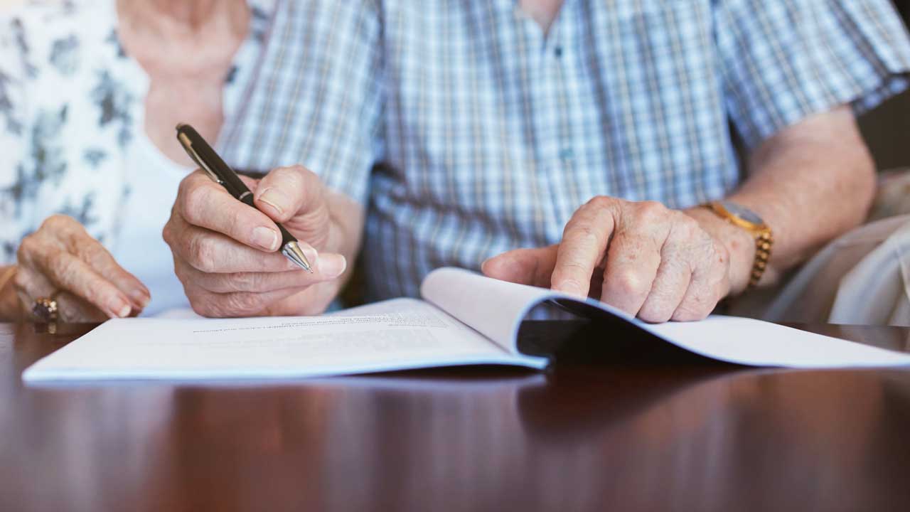 Seniorenpaar unterschreibt ein Dokument