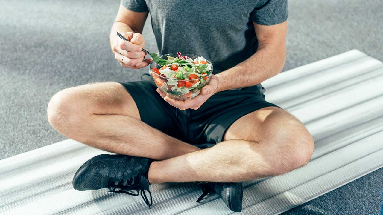 Sitzender Sportler isst Salat
