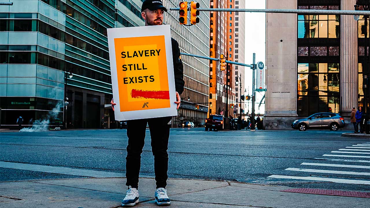 Mann hält Plakat «Slavery still exists», Sklaverei existiert immer noch