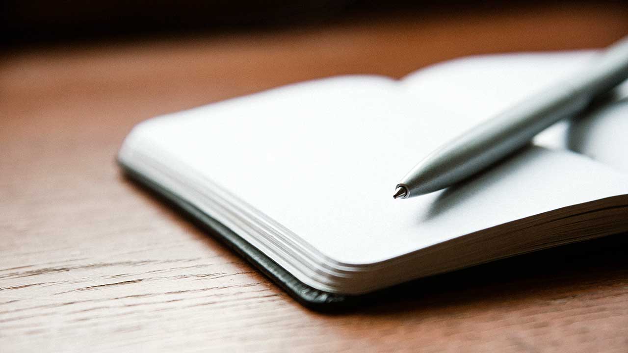 Offenes Tagebuch mit Kugelschreiber auf Holztisch