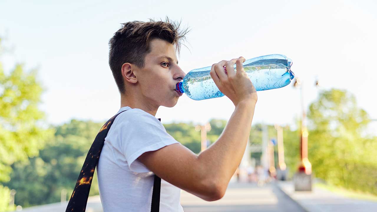 Männlicher Teenanger trinkt Wasser